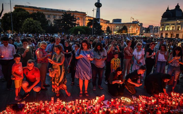 People light candles at a makeshift memorial site in front of the Romanian Ministry of Interior in Bucharest July 27, 2019 to commemorate Alexandra, the 15-year-old girl who has being murdered after she telephoned three times to report her own kidnapping.