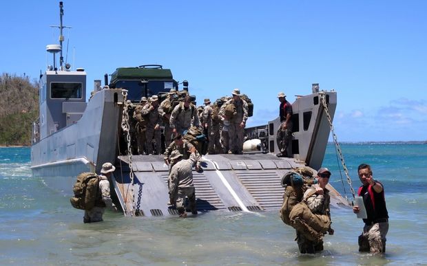 Amphibious Beach Team member Sergeant Dion Lowery guides members of the Humanitarian Assistance and Disaster Relief Light Task Force ashore.
