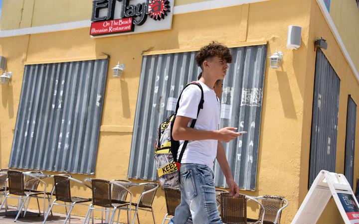 People pass a boarded up business in Hollywood Beach, Florida, as communities prepare for Hurricane Dorian.