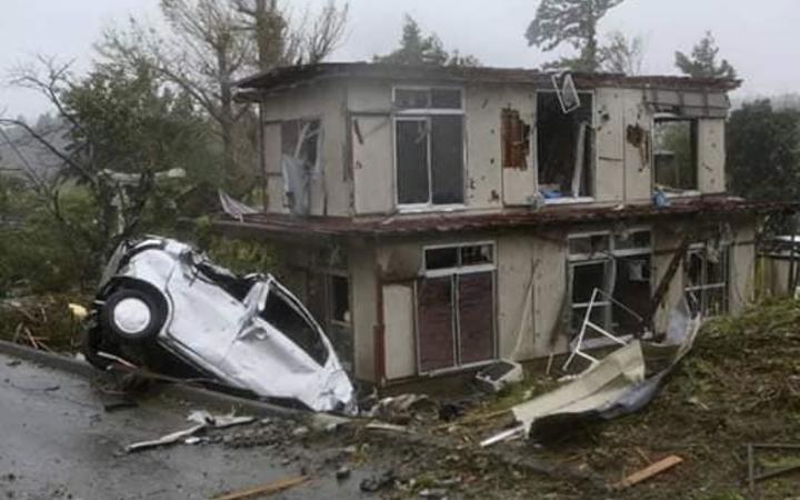 A car sits among debris near a damaged house in Chiba.