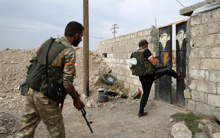 Turkey-backed Syrian fighters break open the front door of a house at a postition that they are holding in the Syrian border town of Ras al-Ain on October 19, 2019.