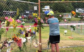 A local man places flowers from his garden on the Whakatāne boat ramp cordon.