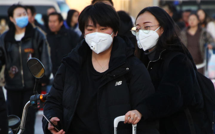People wearing masks head for Beijing Station in Beijing, China on 20 January, ahead of China's Lunar New Year holiday. Tens of thousands of people travel and visit overseas during the holiday. 