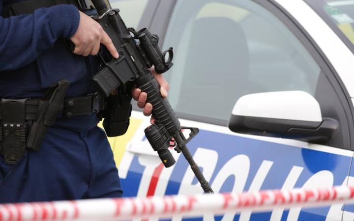 A police officer holds a firearm at the scene of the Hamilton shooting on Tuesday.