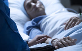 Young woman in hospice care, holding hands in hospital.