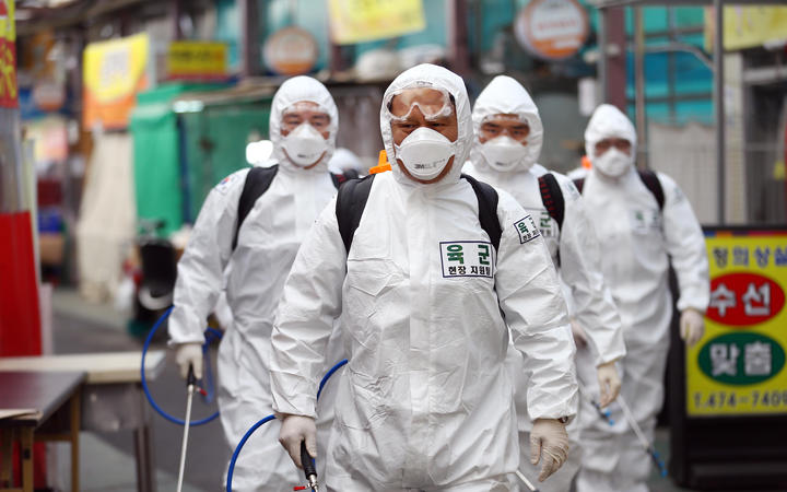 South Korean soldiers wearing protective gear spray disinfectant as part of preventive measures against the spread of the COVID-19 coronavirus, at a market in Daegu.