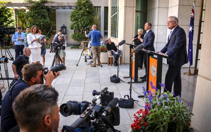 Australian Prime Minister Scott Morrison (R) speaks as he stands with the Australian Treasurer Josh Frydenberg during a press conference at Australia's Parliament House in Canberra on March 22, 2020