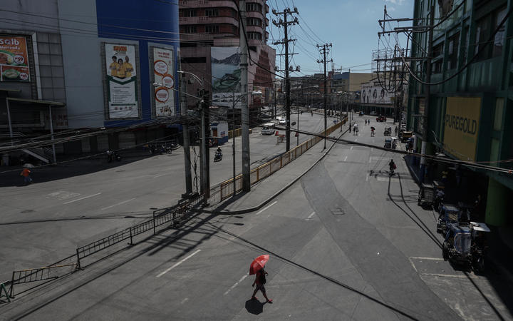A woman with umbrella walks along a deserted street at Divisoria public market in Manila, Philippines on April 01, 2020.