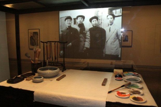 Shi Lu's painting tools on display with photographs at Te Papa