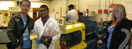 Aaron Lowe and Velram Mohan holding bloodmeal, and Talia Hicks next to an injection moulder