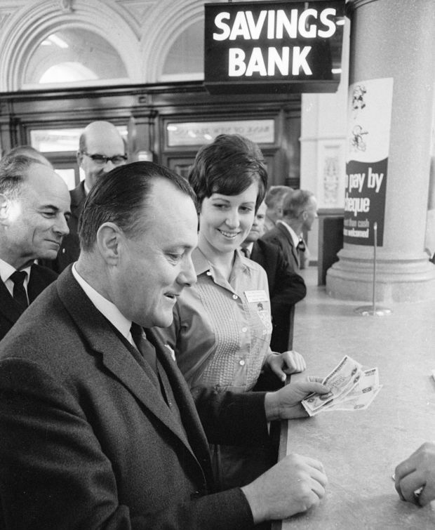 CROP Minister of Finance Robert Muldoon holding four of the new decimal bank notes With him is Bank of New Zealand bank hostess Adrienne Voss