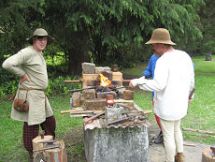 Living history medievalists gater around a fire.