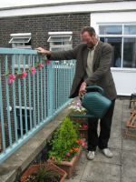 A resident tends the garden at a wet hostel in London