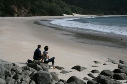 Two tourists sit admiring the pristine beauty of New Chums beach in Coromandel