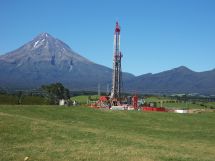 An oil well dominates a green site in front of Mt Taranaki 