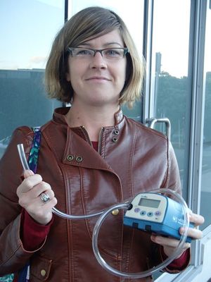 Amber Pearson holds an aerosol monitor for measuring air quality
